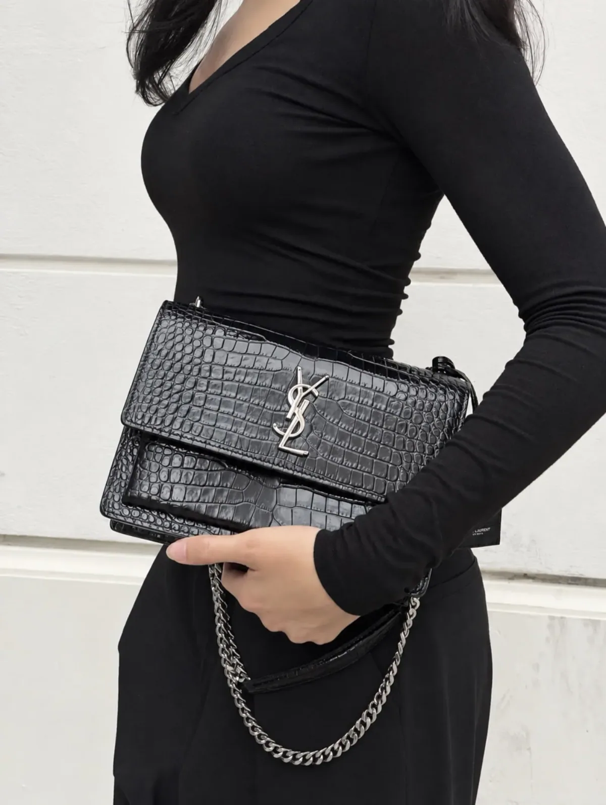 Black crocodile-embossed shoulder bag worn with tailoring