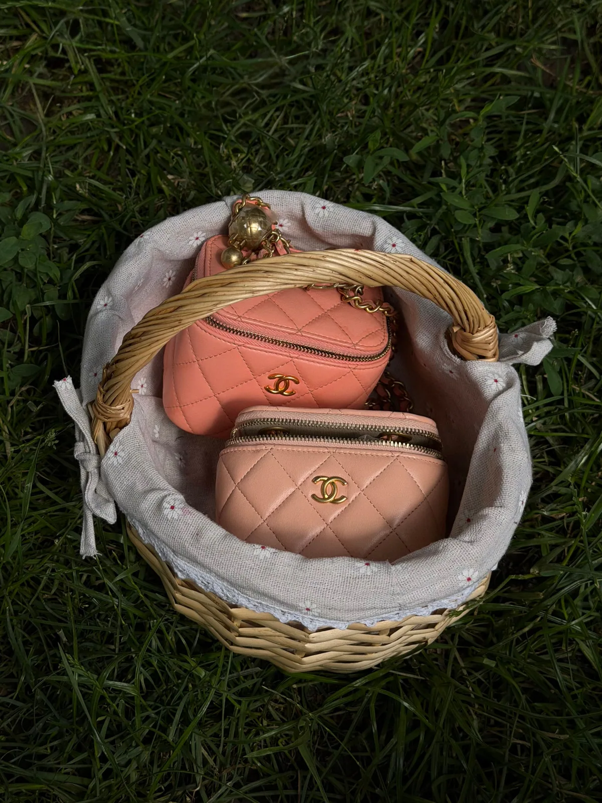Two blush Chanel vanity pouches in a linen-lined picnic basket