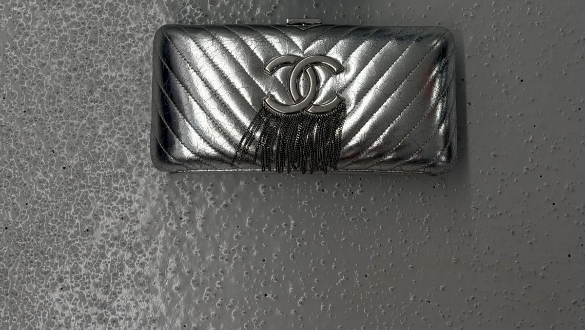 Silver Chanel wallet with chevron stitching and a tassel clasp