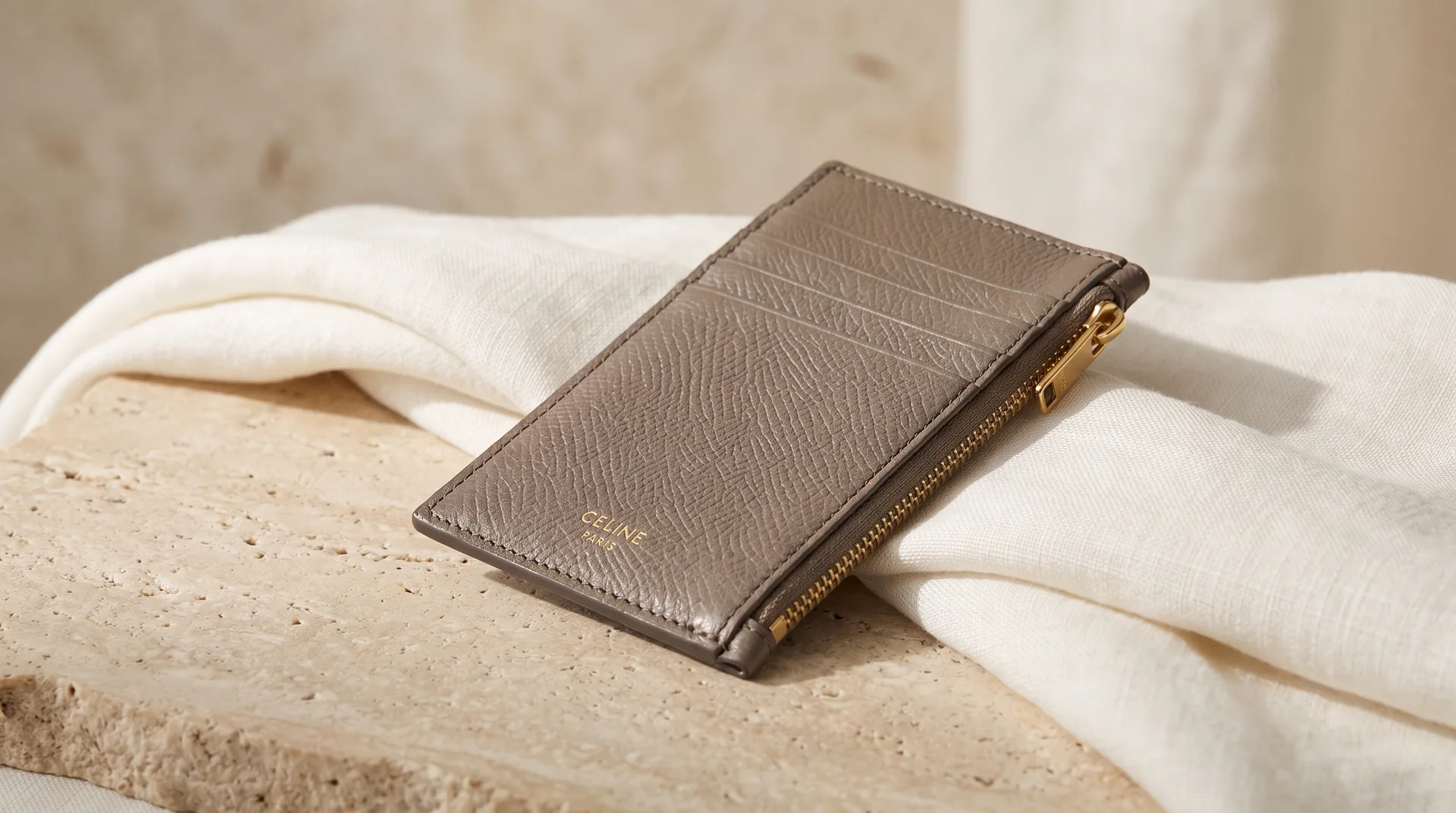 Taupe grained leather cardholder with gold zip on ivory linen